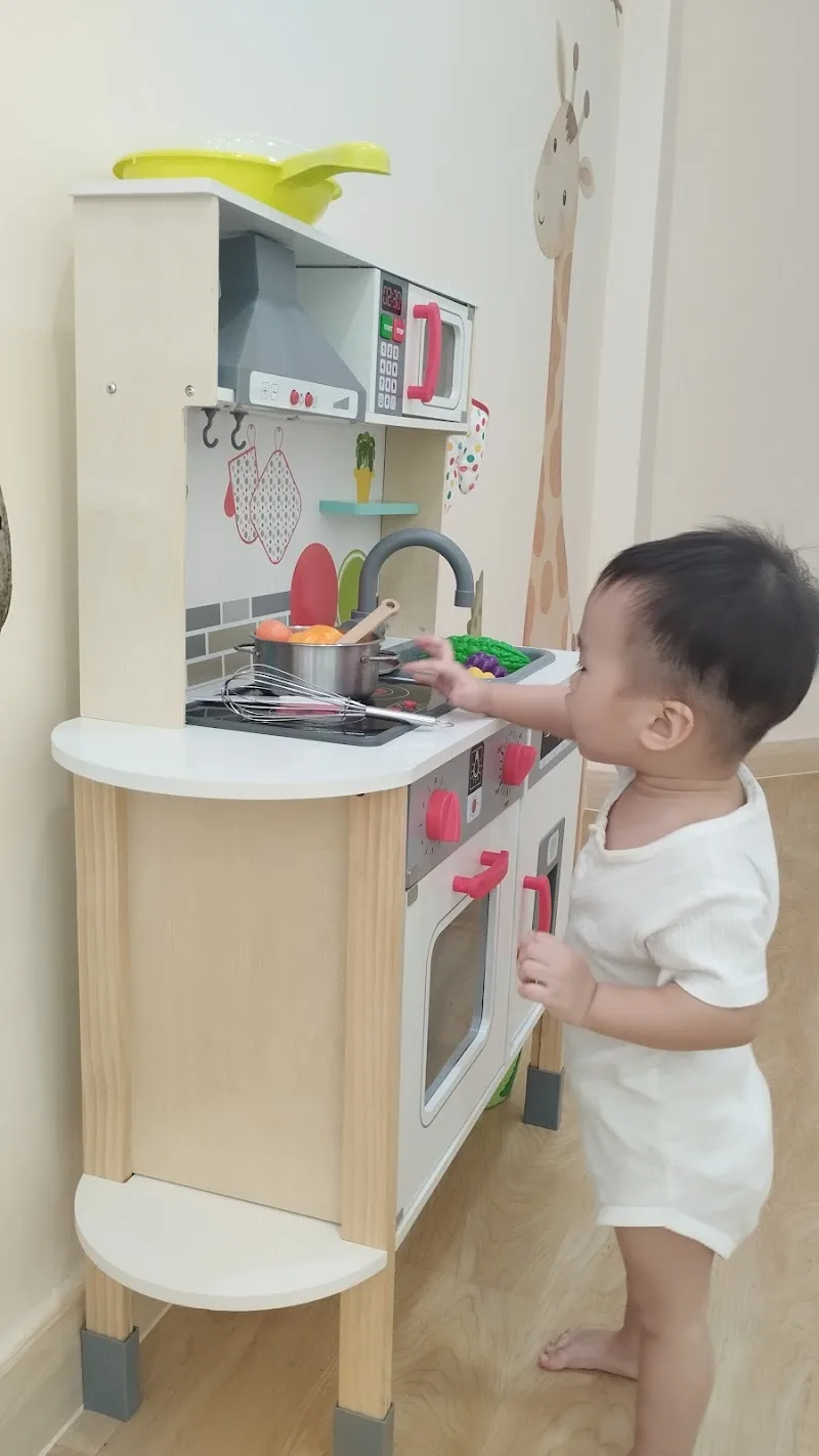 A young child playing at the toy kitchen in the clinic play area