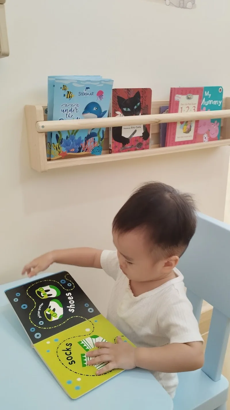 A young child reading a picture book at the play corner